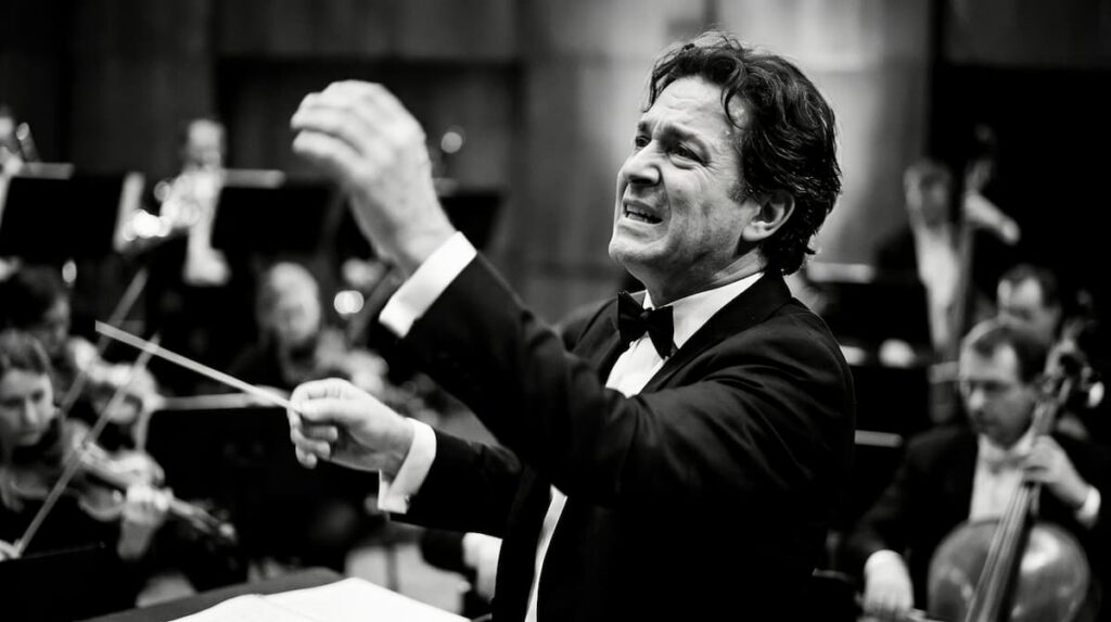 A black and white photograph of passionate conductor conducting an orchestra